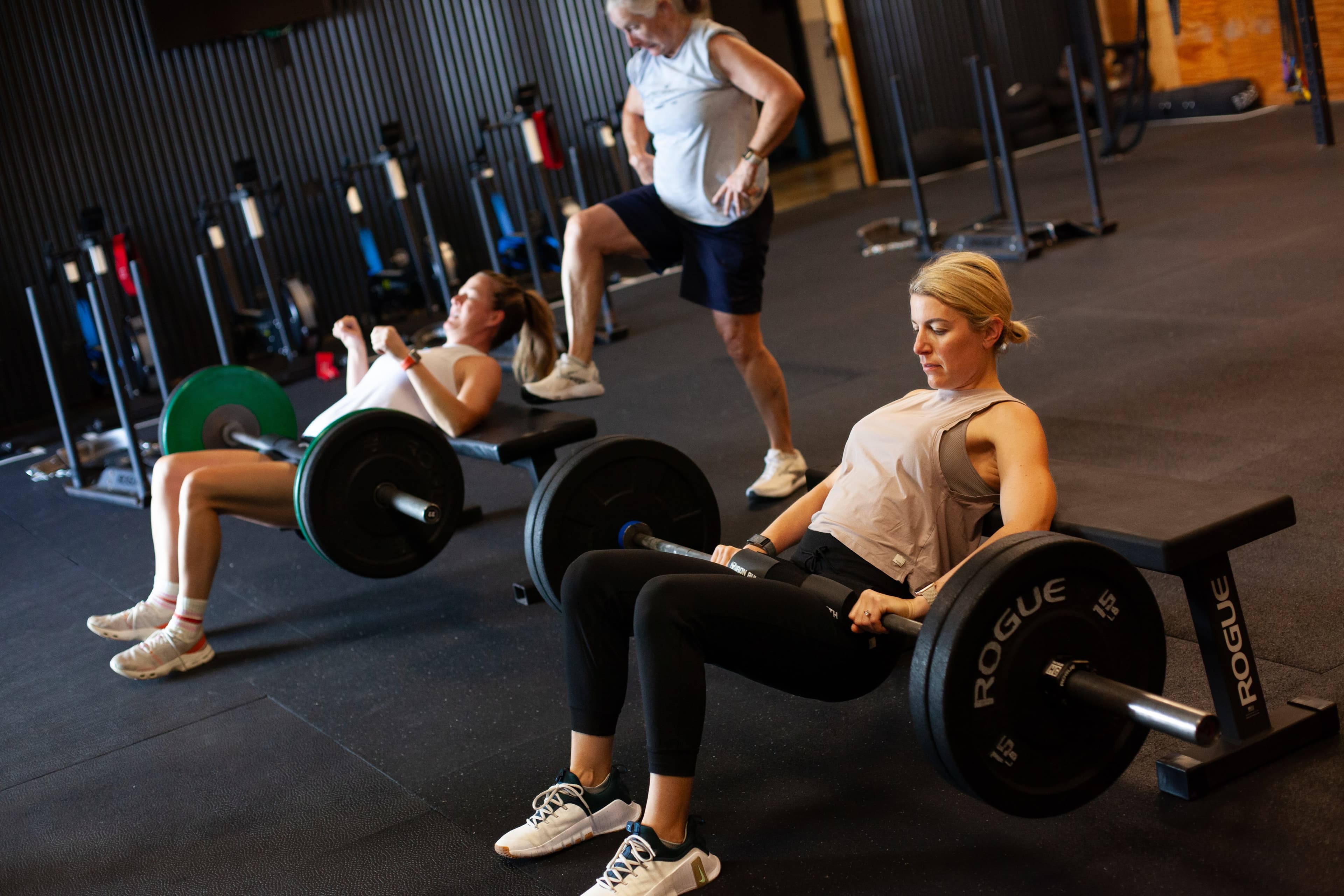 Members doing barbell hip thrusts during a group class